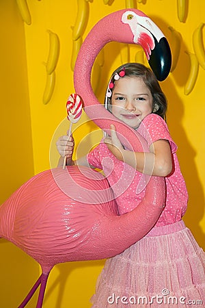 Girl in pink clothes with a Lollipop. In the background, a variety of sweets. Stock Photo