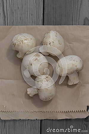 Mushrooms with a brown paper bag on a wooden background. Environmentally friendly recycling packaging Stock Photo