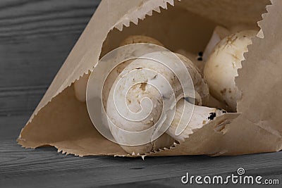 Mushrooms with a brown paper bag on a wooden background. Environmentally friendly recycling packaging Stock Photo