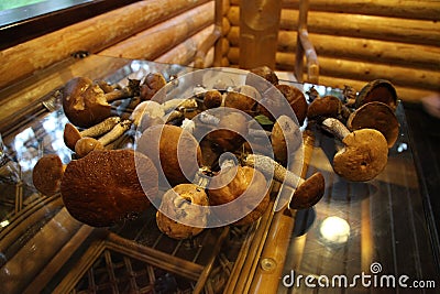 Mushrooms lie on a glass table in a wooden house Stock Photo