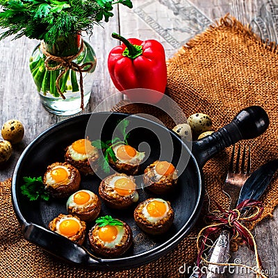 Mushrooms stuffed with quail egg on black pan Stock Photo