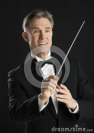 Music Conductor Smiling While Directing With His Baton Stock Photo