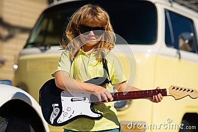 Music kids. Funny little hipster musician child playing guitar. Stock Photo