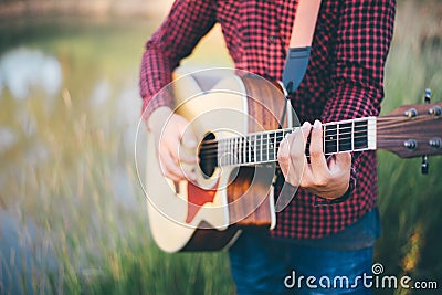 Music in nature, Man playing an acoustic guitar in meadow Stock Photo