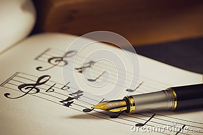 Music notes and old book on wooden table background in morning light. Stock Photo