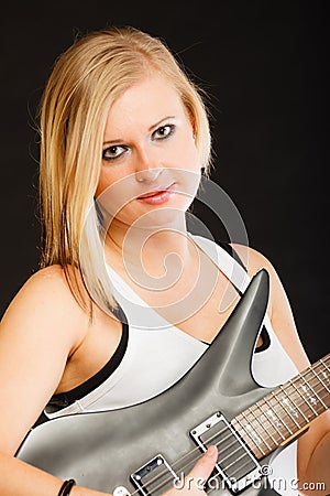 Blonde woman holding electric guitar, black background Stock Photo