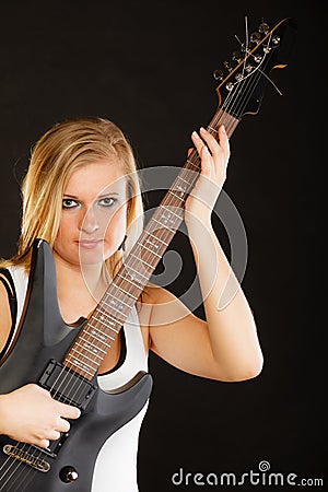 Blonde woman holding electric guitar, black background Stock Photo