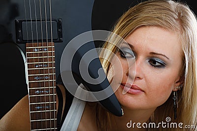 Blonde woman holding electric guitar, black background Stock Photo