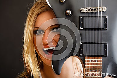 Blonde woman holding electric guitar, black background Stock Photo