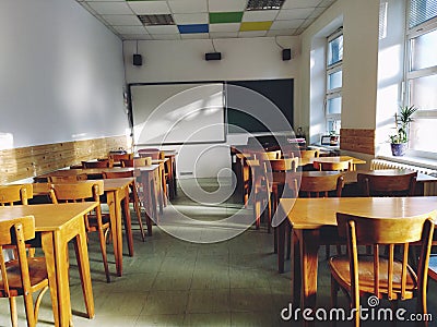 Music solfeggio empty class at school. The sun's rays fall on the floor through the window. Wooden student tables Stock Photo