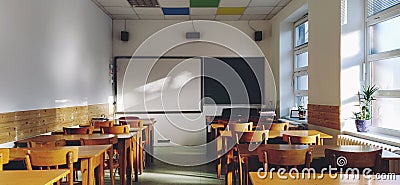 Music solfeggio empty class at school. The sun's rays fall on the floor through the window. Wooden student tables Stock Photo