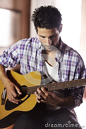 Music soothes the soul. A handsome young musician playing a guitar. Stock Photo