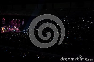 A musical concert of the group with color music, a crowd of spectators and multi-colored lighting Editorial Stock Photo