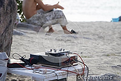 Musical equipment on the beach. DJ console and microphone with a bunch of wires in stone. Sound mixer. The concept of creating Stock Photo