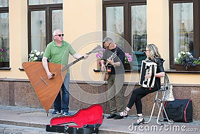 A musical group of three people on an old European street. The band consists of two men and one girl. Men with a double bass and a Editorial Stock Photo