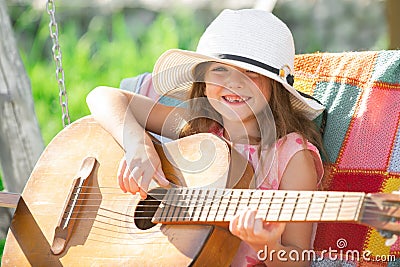 Musician child playing guitar. Kid girl singing and playing guitar outside. Kids music and songs. Smiling child playing Stock Photo