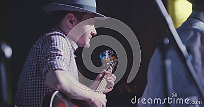 Musician in hat plays guitar in night club, close up Stock Photo