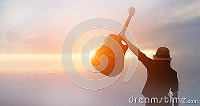 Musician holding acoustic guitar in hand of silhouette on sunset Stock Photo