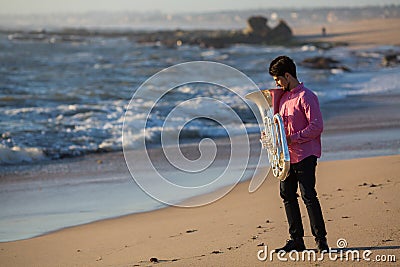Musician with musical instrument Tuba on romantic sea shore. Concert. Stock Photo