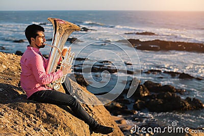 Musician play to musical instrument Tuba on romantic sea shore. Hobby. Stock Photo