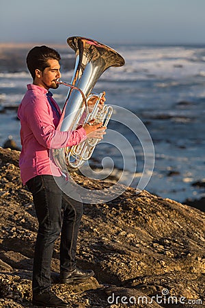 Musician play to musical instrument Tuba on romantic sea shore. Hobby. Stock Photo