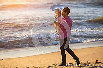 Musician playing musical instrument Tuba on the sea beach. Concert. Stock Photo