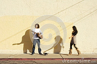 Musician on Sidewalk and Woman Pedestrian Stock Photo