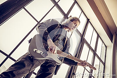 Musician wearing jeans and black leather jacket playing the guitar Stock Photo