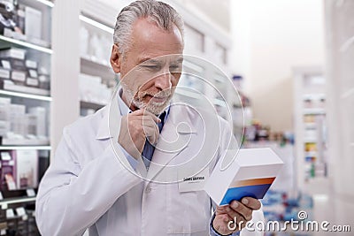 Musing male pharmacist discovering new drug Stock Photo