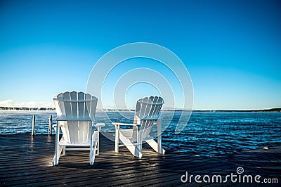 Muskoka Chairs on a dock with sun rising and mist Stock Photo