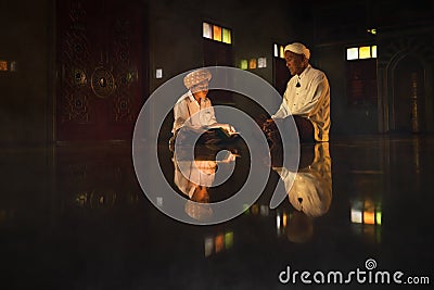 Muslim boy sitting in mosque with islamic teacher learning koran book Stock Photo