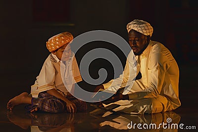 Muslim boy sitting in mosque with islamic teacher learning koran book Stock Photo