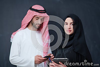 Muslim couple using modern technology in front of black chalkboard Stock Photo