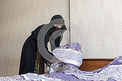 Muslim immigrant woman making bed Stock Photo