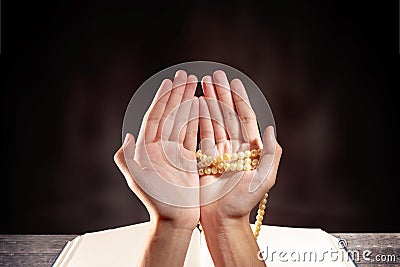 Muslim man praying with prayer beads on his hands in front of the opened quran Stock Photo