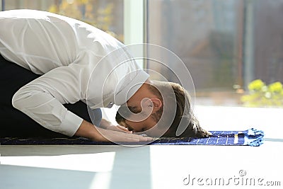 Muslim man in suit praying on rug Stock Photo