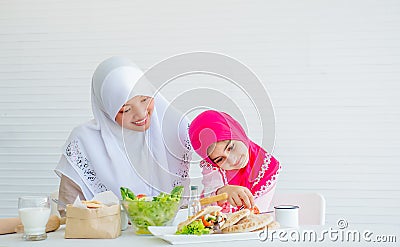 Muslim mother has action for motivating her daughter to eat vegetable, especially fresh tomatoes for good health Stock Photo
