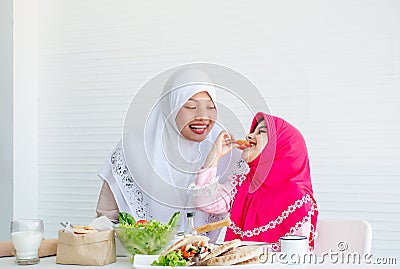 Muslim mother has action for motivating her daughter to eat vegetable, especially fresh tomatoes for good health Stock Photo