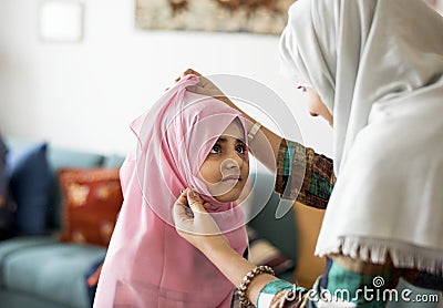 Muslim mother putting on a hijab on her little daughter Stock Photo