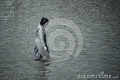 Muslim woman taking a swim in the sea full covered with clothes Editorial Stock Photo