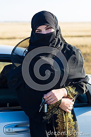 Muslim woman stands near the car with keys hand. Stock Photo