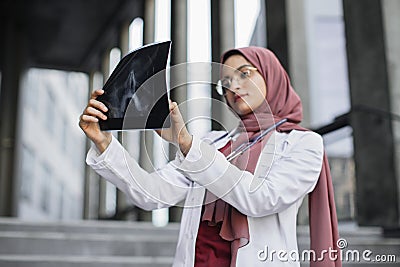 Muslim woman surgeon, looking at X-Ray radiography of patient& x27;s head skull Stock Photo