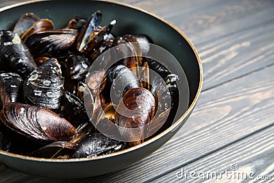 Mussels with parsley and garlic in wog pan on wooden table Stock Photo