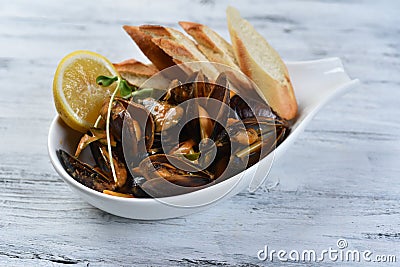 mussels in a shell with sauce, croutons, lemon and sprouts in a white plate Stock Photo