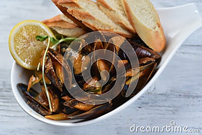 mussels in a shell with sauce, croutons, lemon and sprouts in a white plate Stock Photo