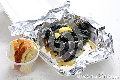 Mussels in wine, butter and garlic, served with bread. Clams in a take-away carton box, on white background, top view. Stock Photo