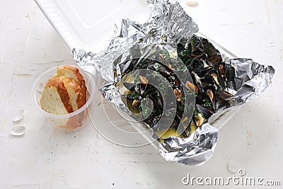 Mussels in wine-butter sauce, served with bread. Clams in a take-away carton box, on white background, top view. Stock Photo