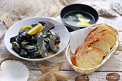 Mussels in wine-butter sauce, sprinkled with parsley, served with bread. Clams in a bowl, on white wood background. Stock Photo