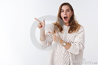 Must see. Portrait amused astonished speechless attractive female model wearing sweater drop jaw impressed pointing Stock Photo