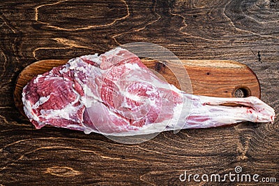 Mutton meat. Raw whole lamb leg thigh on butcher board. Wooden background. Top view Stock Photo